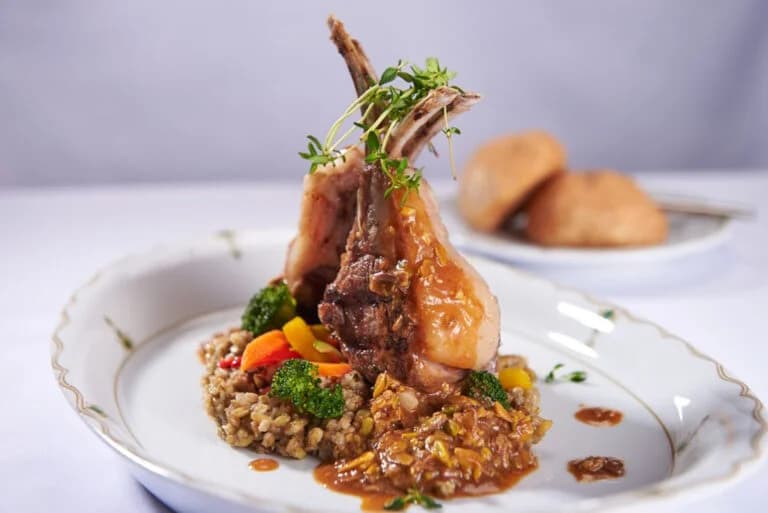 Herb-crusted lamb chops plated with sauce