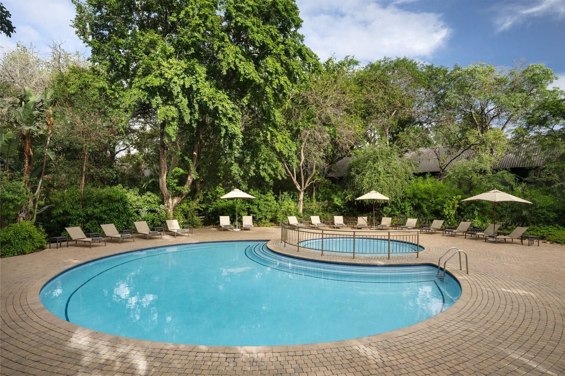 Freeform family pool with children's pool, loungers and tropical garden